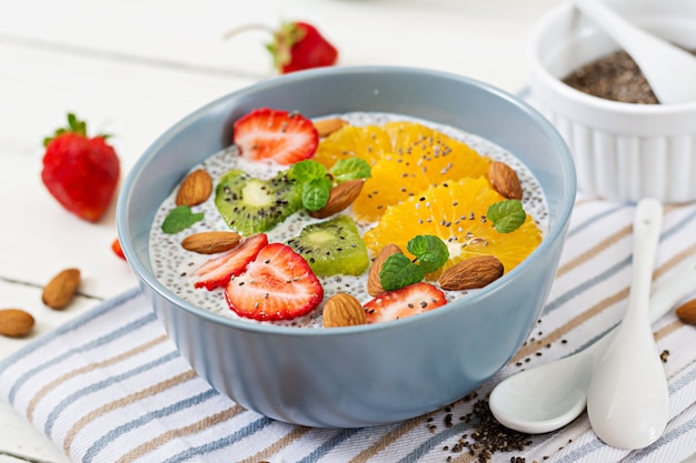 Disintossicante e salutare supercibi colazione in una ciotola. Budino vegano di semi di chia di latte di mandorle con fragole, arancia e kiwi.