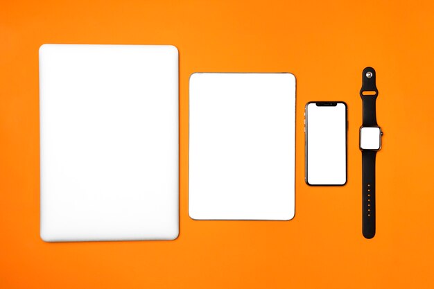 Dispositivi piatti laici su sfondo arancione
