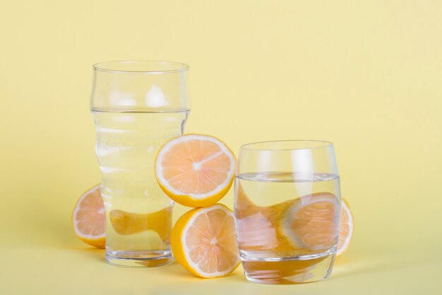 Disposizione con bicchieri d'acqua e limoni