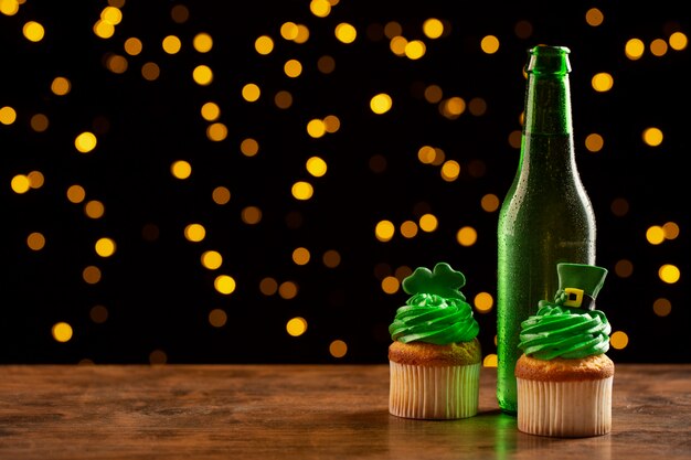 Disposizione con bottiglia di birra e cupcakes