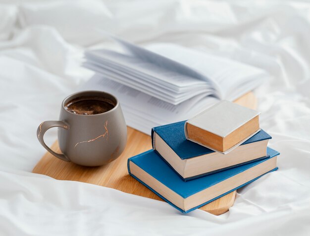 Disposizione con libri e tazza a letto