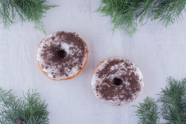 Disposizione delle ciambelle in mezzo a foglie di cipresso su sfondo bianco.