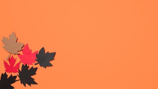 Disposizione di carta delle foglie di autunno su fondo arancio con lo spazio della copia