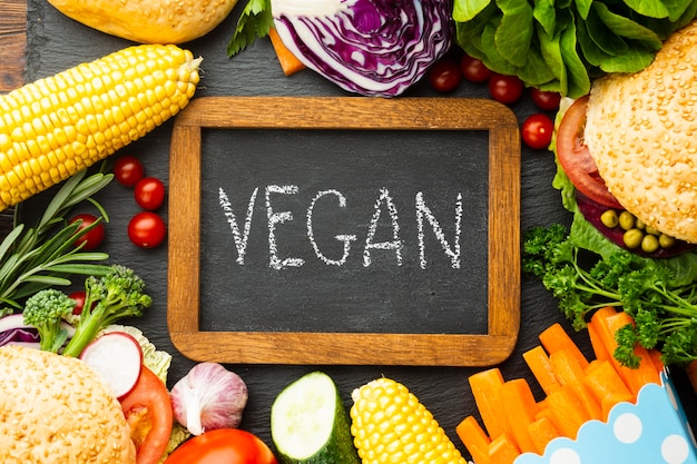 Disposizione di cibo sano con scritte vegan sulla lavagna