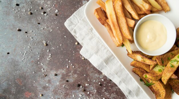 Disposizione di deliziose patatine fritte con condimento bianco