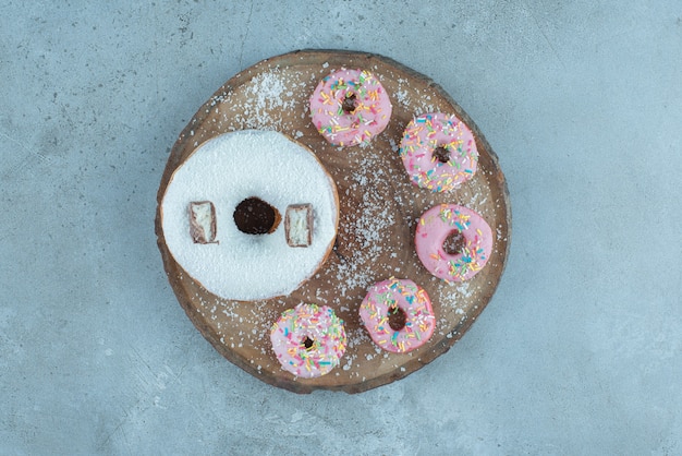 Disposizione di una ciambella grande e più piccole su una tavola di legno su marmo.