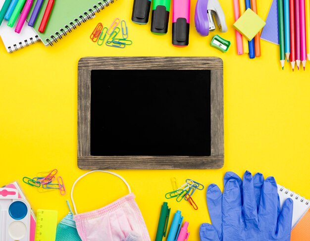 Disposizione piana degli elementi essenziali della scuola con guanti e matite colorate