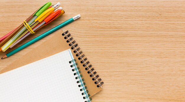Disposizione piana degli elementi essenziali della scuola con matite e quaderni