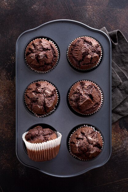 Disposizione piana dei muffin al cioccolato in vassoio con il panno