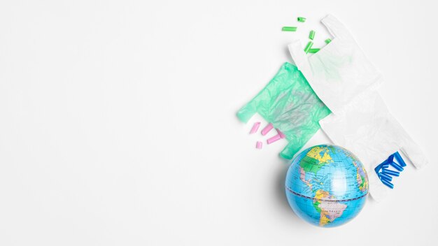 Disposizione piana del globo della terra con i sacchetti di plastica e lo spazio della copia