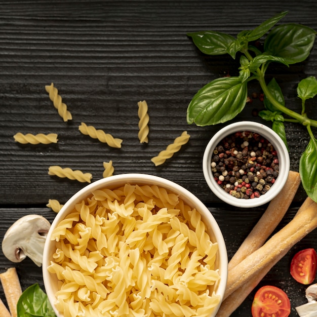 Disposizione piana del pepe e del grissini della pasta di fusilli sulla tavola di legno