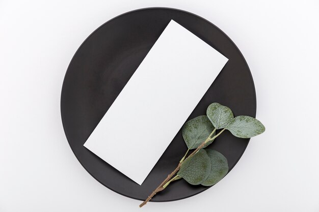 Disposizione piana della carta in bianco del menu sul piatto con la pianta