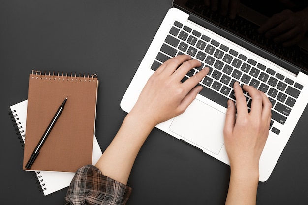 Disposizione piana della stazione di lavoro con le mani su laptop e notebook