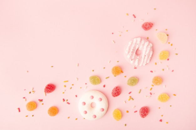 Disposizione piana di ciambelle glassate con caramelle e copia spazio