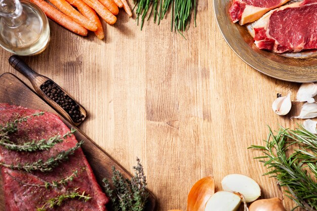 Disposizione piana di differenti carni e verdure crude differenti sulla tavola di legno. Preparazione del cibo. Proteine naturali.