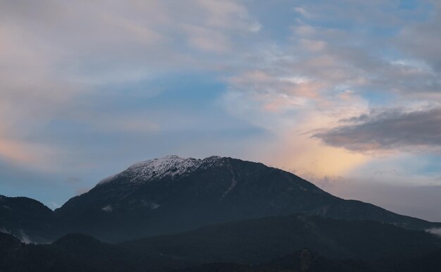 Distanti cime montuose nella neve contro l'idea del paesaggio montano del cielo al tramonto per uno sfondo o uno sfondo