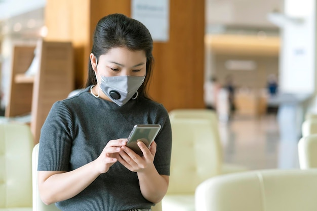 Distanziamento sociale con la protezione dai virus della maschera facciale da indossare per le donne asiatiche in attesa di sedersi su una sedia con una distanza di spazio per prevenire la diffusione del virus