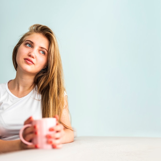 Distogliere lo sguardo della tazza della tenuta della donna