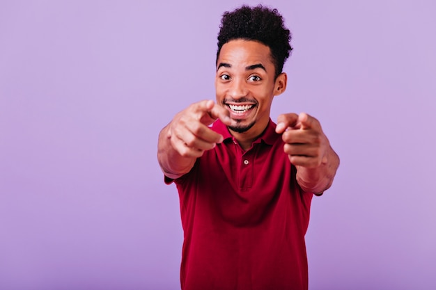 Dito puntato ragazzo africano ispirato. ridendo positivo uomo nero sorridente.