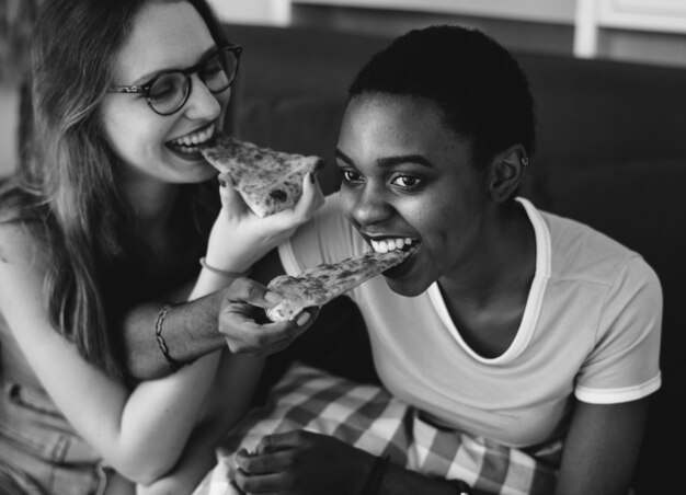 Diverse donne che mangiano pizza insieme