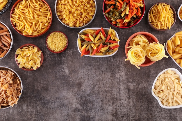 diversi bambini di pasta in vista dall'alto di piatti con copia spazio sulla superficie grigia