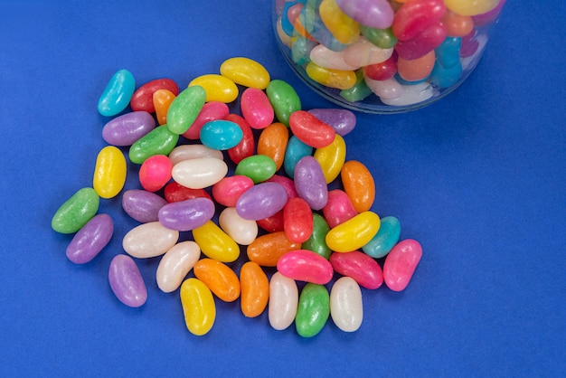 Diversi Jelly Beans sulla superficie blu all'interno della pentola di vetro