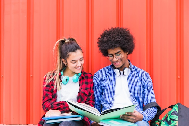 Diversi studenti che studiano insieme contro uno sfondo arancione