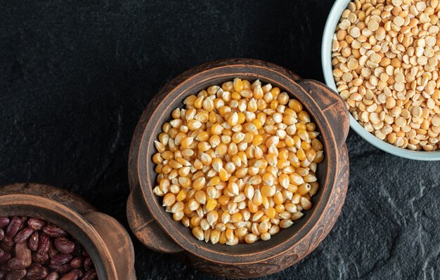 Diversi tipi di fagioli crudi su pentole antiche.