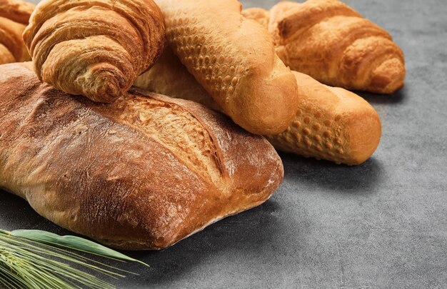 Diversi tipi di panini su tavola grigia primo piano Cucina o poster design per una panetteria locale Baguette croissant e ciabatta vari tipi di pane appena sfornato
