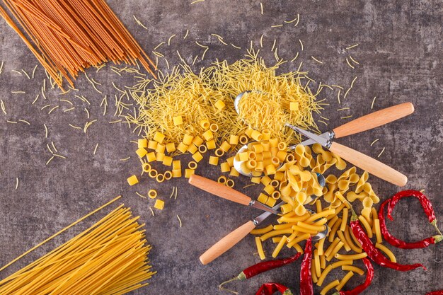 diversi tipi di pasta con cucchiai vista dall'alto