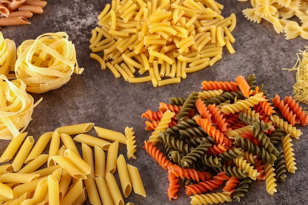 diversi tipi di pasta cruda isolati sulla superficie grigia