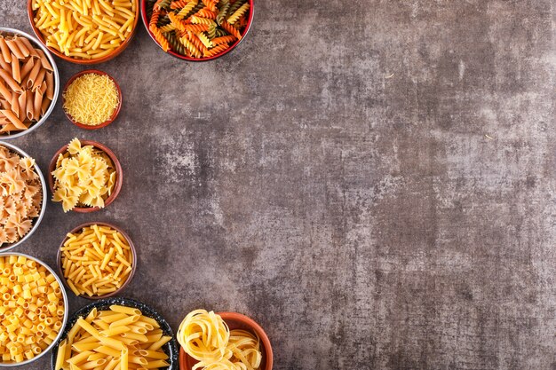 diversi tipi di pasta in ciotole su superficie grigia