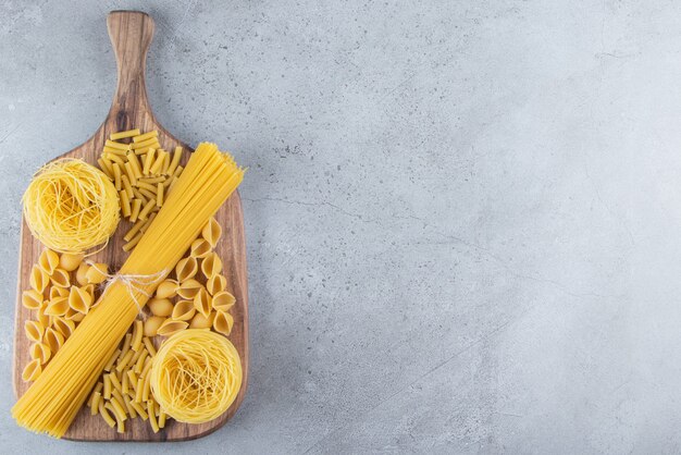 Diversi tipi di pasta secca cruda su uno sfondo di pietra.