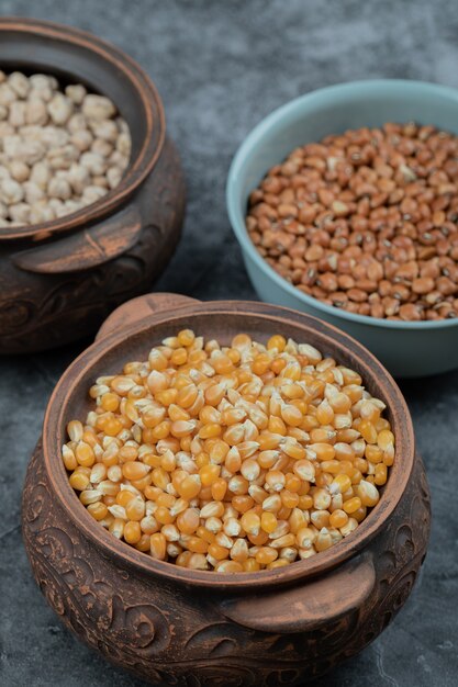 Diversi tipi di semi di fagioli, lenticchie, piselli in piatti sul nero.