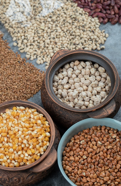 Diversi tipi di semi di fagioli, lenticchie, piselli in piatti sul nero.