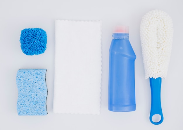 Diversi tipi di spugne con bottiglia detergente blu su sfondo bianco