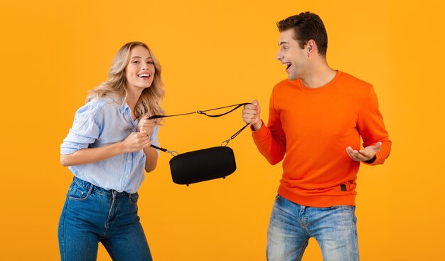 Divertente giovane coppia in lotta per un altoparlante wireless che ascolta musica in stile colorato