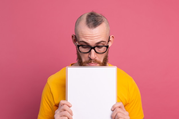 Divertente giovane uomo guarda fuori gli occhi bianco vuoto vuoto cartellone per il contenuto promozionale isolato girato in studio