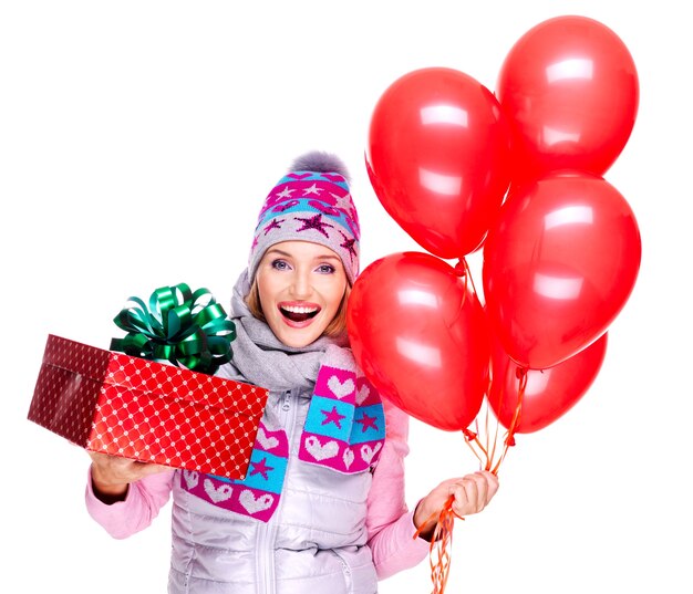 Divertimento felice giovane donna con confezione regalo rossa e palloncini isolati su bianco