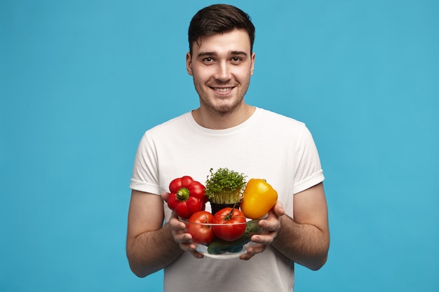 Divertiti. Ragazzo giovane attraente felice felice che sceglie stile di vita sano e cibo crudo biologico