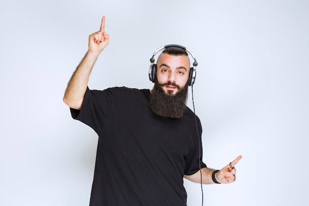 Dj con la barba che indossa le cuffie e punta verso l'alto.