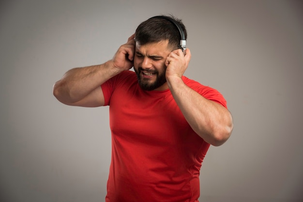 Dj maschio in camicia rossa che indossa le cuffie e cantando.