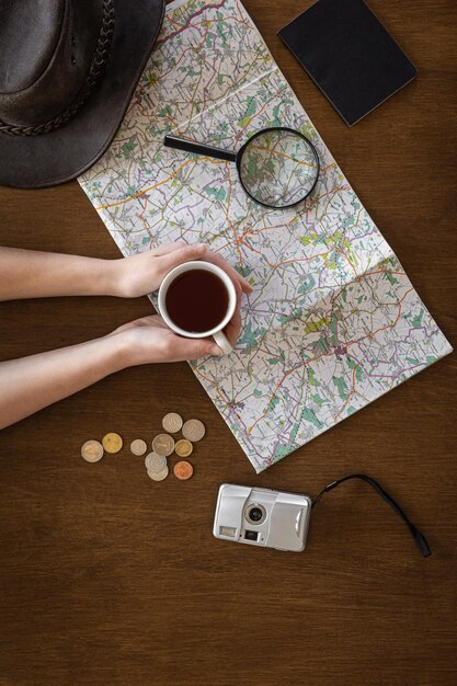 Documenti con lente d'ingrandimento della mappa piatta e una tazza di caffè nelle mani di una donna