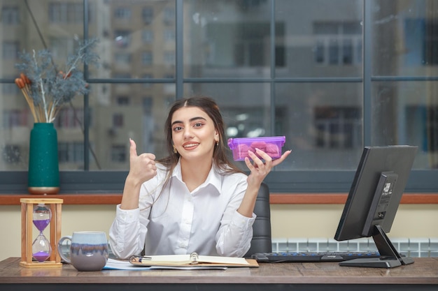 Dolce ragazza con contenitore per biscotti e gesto pollice in su