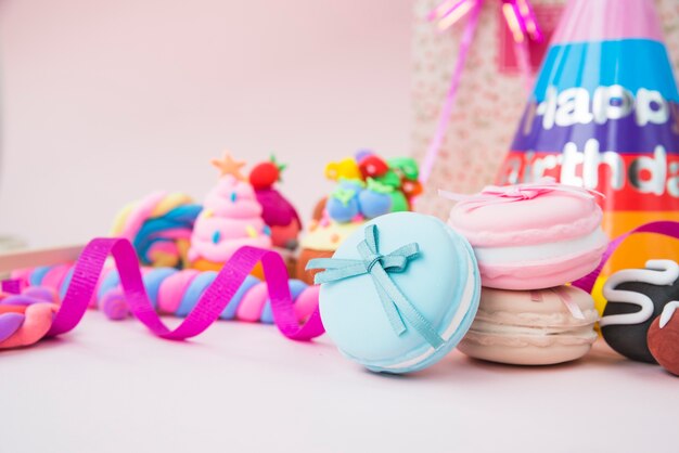 Dolci caramelle; amaretto; nastri e cappello di compleanno su sfondo rosa