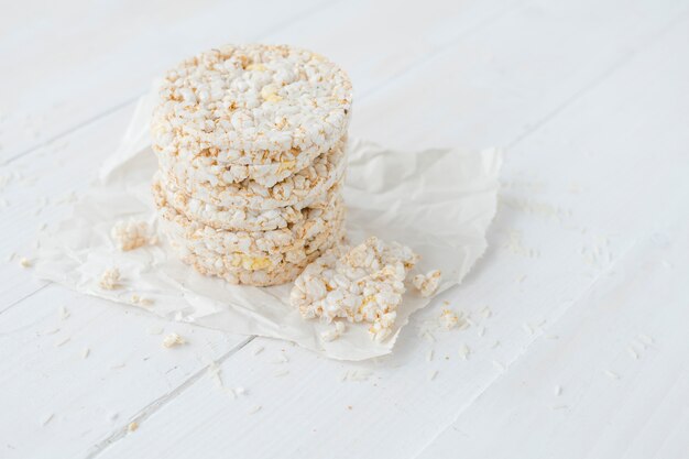 Dolci di riso soffiati rotti e rotondi sulla tavola di legno bianca