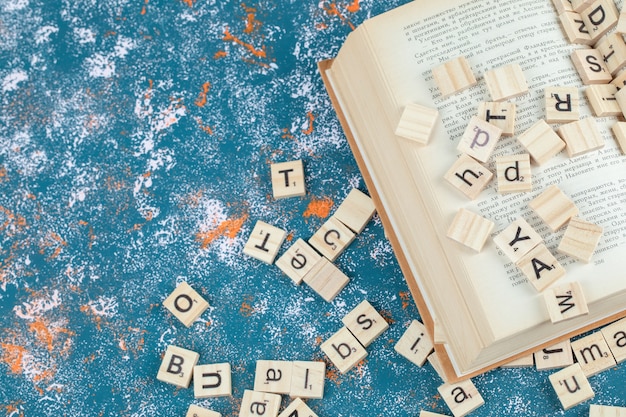 Domino lettera in legno e isolato sulla superficie del modello blu