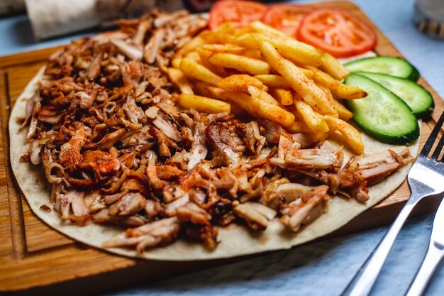 Doner di vista laterale sulla pita con il cetriolo e il pomodoro freschi delle patate fritte