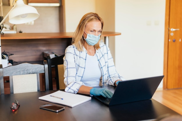 Donna a casa durante la quarantena che lavora al computer portatile