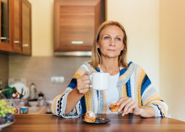 Donna a casa durante la quarantena che mangia caffè